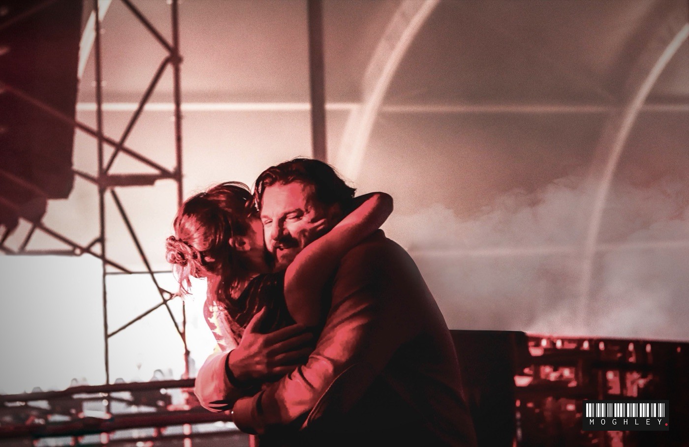 Two people embracing at a festival, warm red lighting